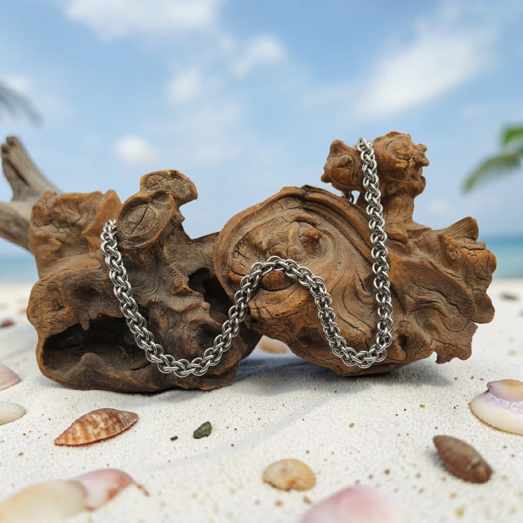 Sanctuary Studio handcrafted stainless steel Jens Pind Linkage 3 chainmaille necklace draped over driftwood on sand.