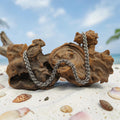 Sanctuary Studio handcrafted stainless steel Jens Pind Linkage 3 chainmaille necklace draped over driftwood on sand.